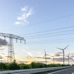 Torre eléctrica y aerogeneradores en un paisaje de energías renovables para representar el mercado energético en España
